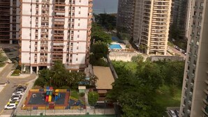A high-rise residential building with multiple balconies, a basketball court, and a view of the sea. - Barra da Tijuca 2 Bedroom Apartment on the Beach (Rio de Janeiro)