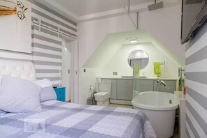 A bedroom with a bed, a large window, a bathroom with a bathtub, and a toilet. - Barra da Tijuca 2 Bedroom Apartment on the Beach (Rio de Janeiro)