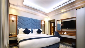 Habitación de hotel con una cama grande, un escritorio, una silla, un televisor y un espejo.