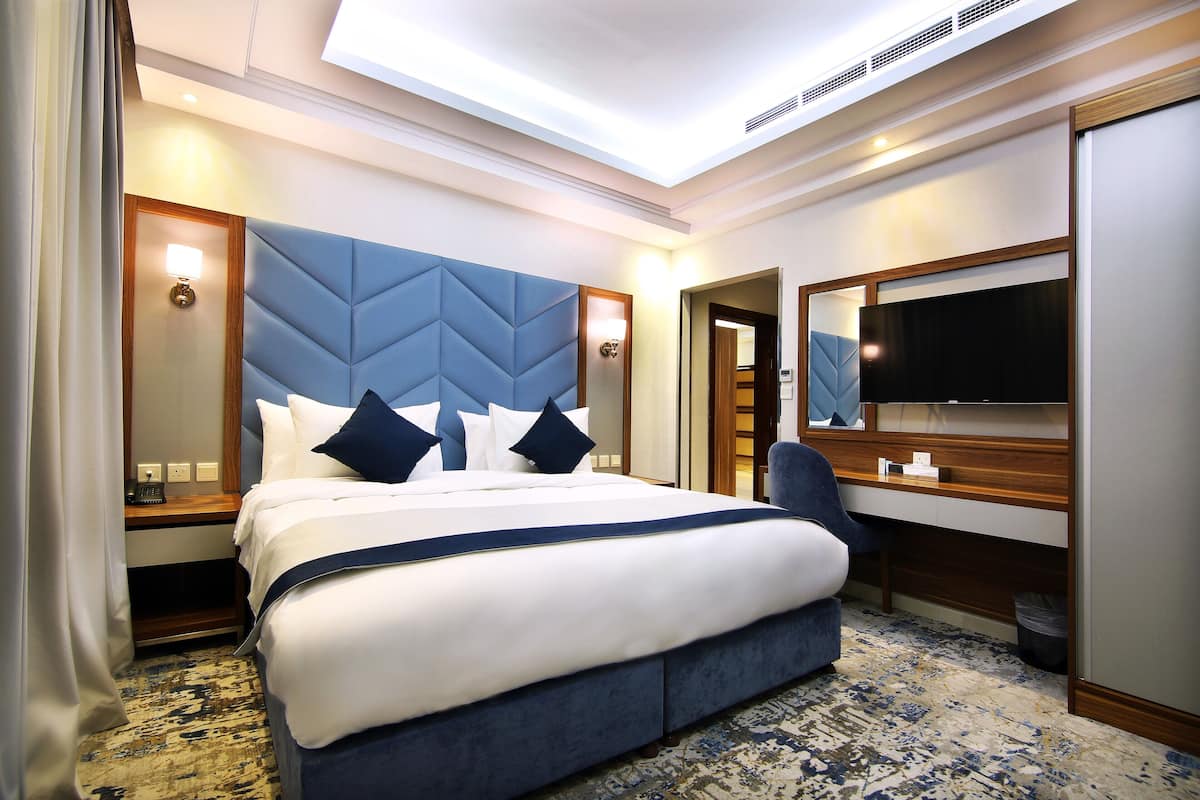 Een hotelkamer met een groot bed, een bureau, een stoel, een televisie en een spiegel.