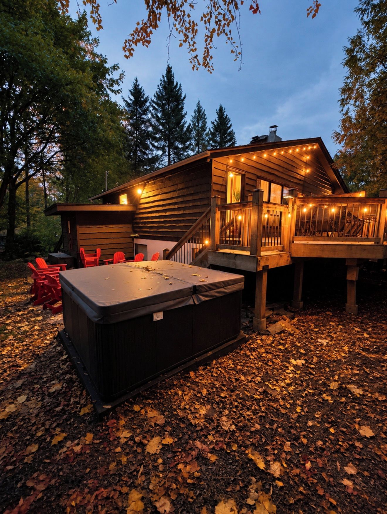 A wooden cabin with a hot tub, outdoor seating, and a deck.