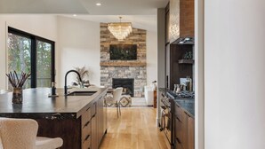 Une cuisine moderne avec une cheminée en pierre, des meubles en bois et un grand îlot central.