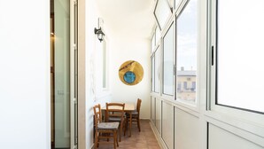 A narrow corridor with a dining area featuring a table and four chairs, a wall-mounted light fixture, and a large window with a view of buildings. - 4004 Casa La Luna by Barbarhouse (Bari)