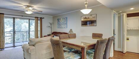 A dining area with a table and chairs, a sofa, and a ceiling fan.
