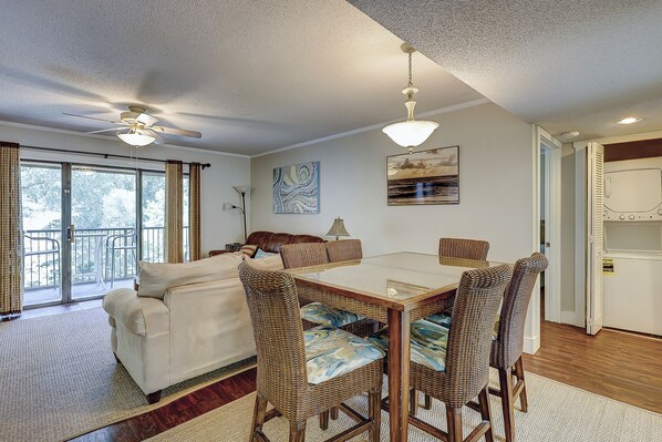 A dining area with a table and chairs, a sofa, and a ceiling fan.
