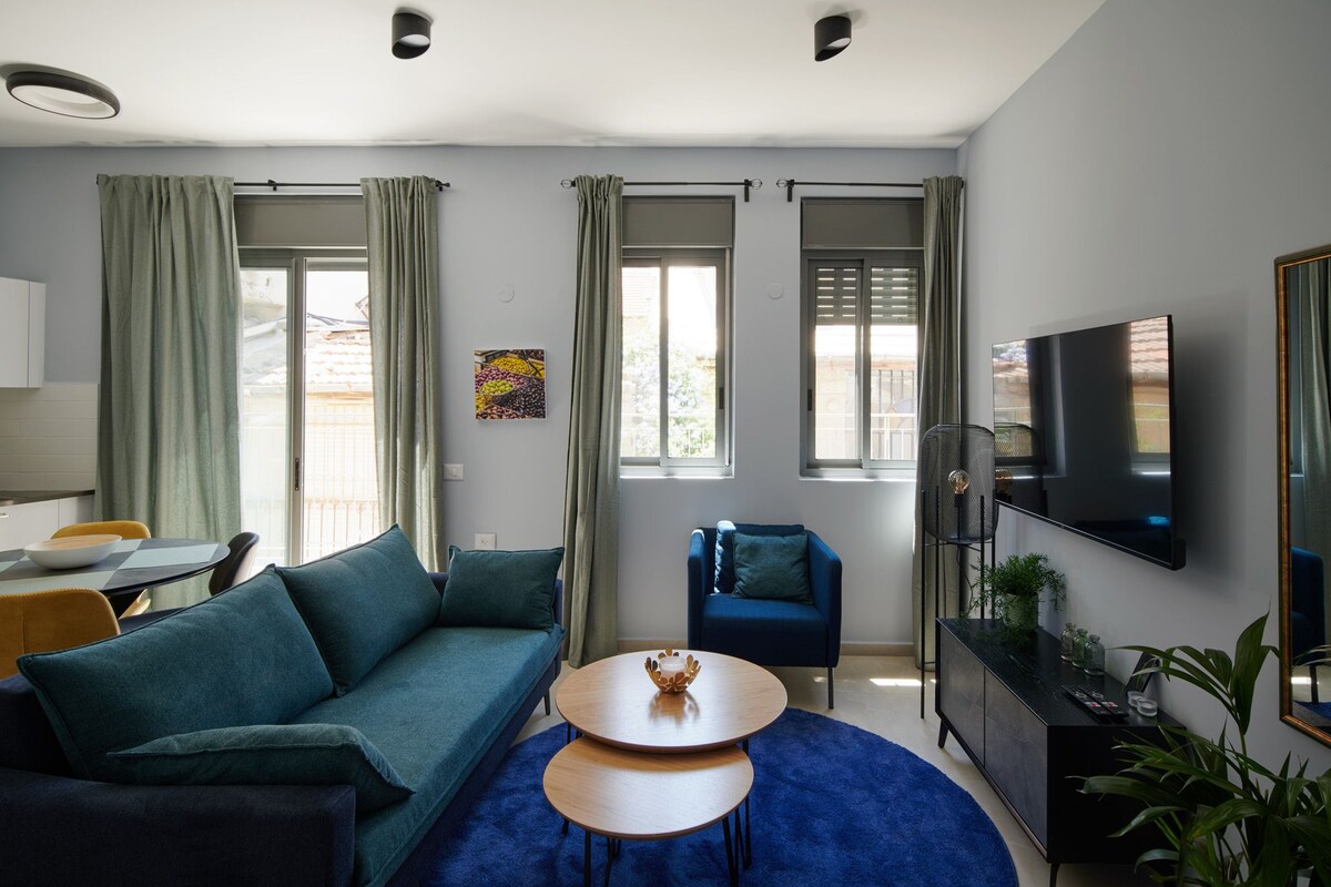 Una sala de estar moderna con un sofá, una mesa de centro, un televisor y un comedor con una mesa y sillas.