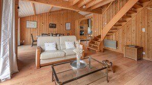 A wooden interior with a sofa, a glass coffee table, and a staircase. - House for 8 people - 300m from the beach (Saint-Michel-Chef-Chef)