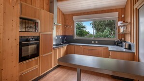 A modern kitchen with wooden cabinetry, a built-in oven, a large window, and a stainless steel countertop. - House for 8 people - 300m from the beach (Saint-Michel-Chef-Chef)