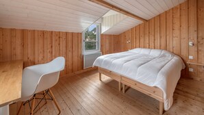 A wooden-paneled room with a bed, a white chair, and a window. - House for 8 people - 300m from the beach (Saint-Michel-Chef-Chef)