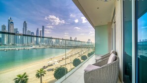 A balcony with wicker furniture overlooking a beach and a city skyline. - Sunrise Bay - Mint Stay (Dubai)