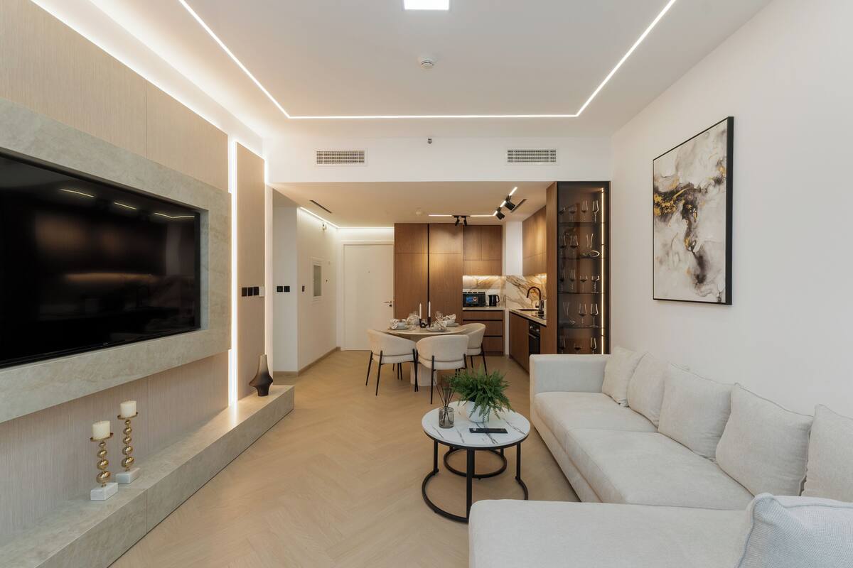 Una sala moderna con televisor de pantalla plana, un sofá, una mesa de centro y una zona de comedor con sillas.