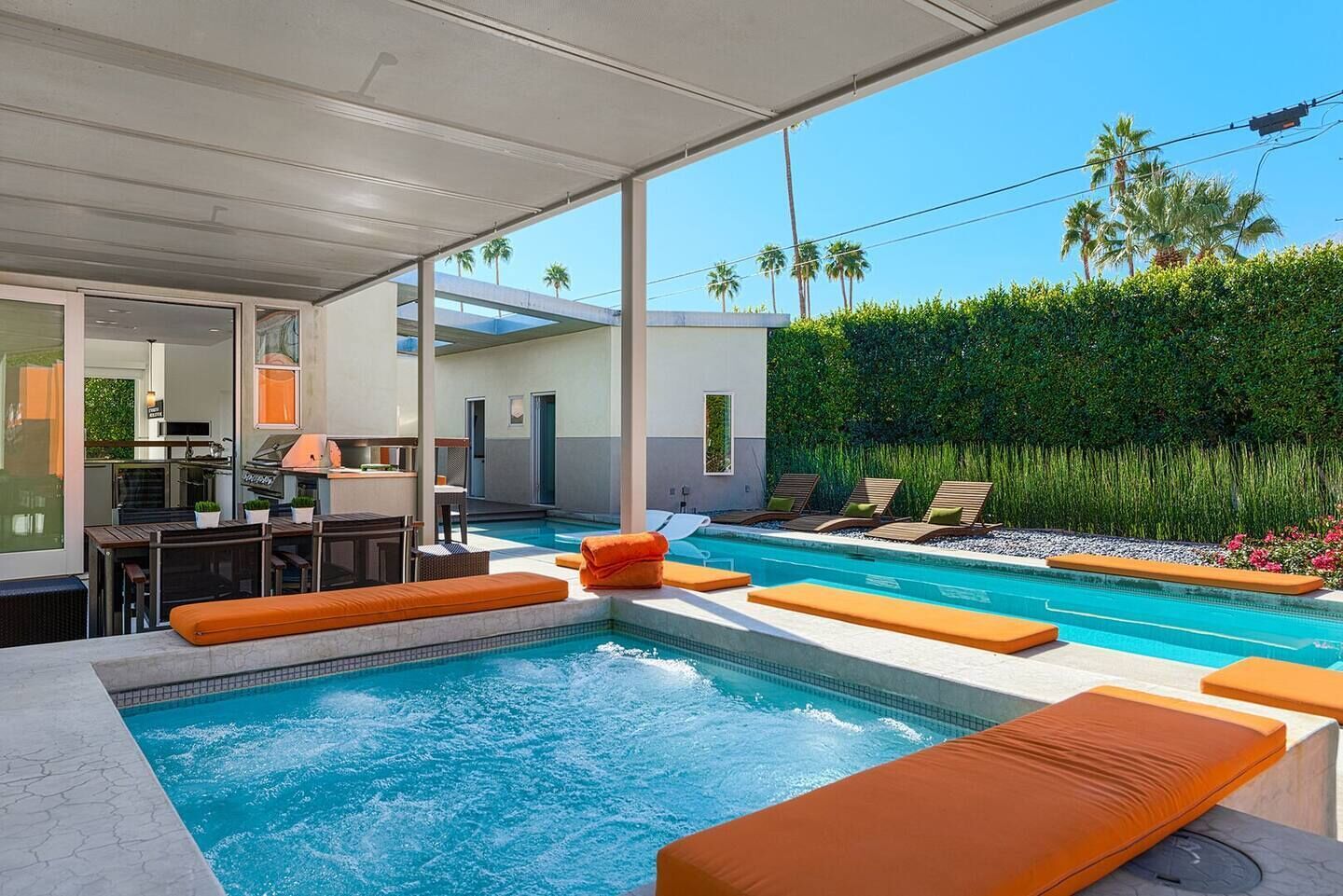 A modern outdoor pool area with lounge chairs and a barbecue setup.