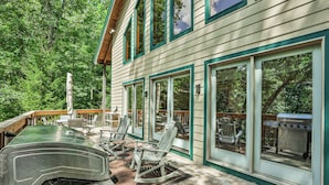 Une terrasse couverte, aménagée avec du mobilier d’extérieur, un gril et un barbecue.