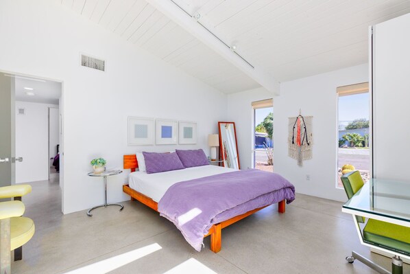A modern bedroom with a bed, bedside table, and a view of the outdoors.