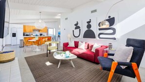 Una sala de estar moderna con un sofá rojo, una mesa de centro y un comedor con sillas naranjas.