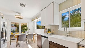 A modern kitchen with white cabinetry, a dishwasher, and a large window. - Sept Special Offer! 30+ Night Stay W/Pool/Hot Tub (Palm Springs)