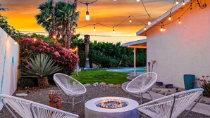 A patio with a fire pit, white chairs, and string lights against a sunset backdrop. - Sept Special Offer! 30+ Night Stay W/Pool/Hot Tub (Palm Springs)