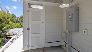Un cuarto de servicio con una puerta blanca, panel eléctrico e iluminación exterior.