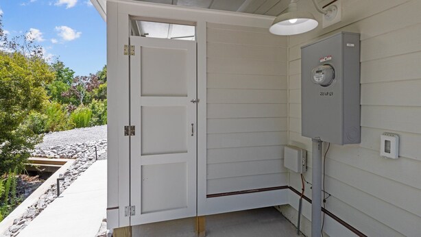 Une pièce utilitaire avec une porte blanche, un tableau électrique et un luminaire extérieur.