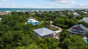 Un quartier résidentiel où les maisons sont entourées d’une végétation luxuriante, et d’où l’on a une vue dégagée sur l’océan, avec une piscine visible au loin.