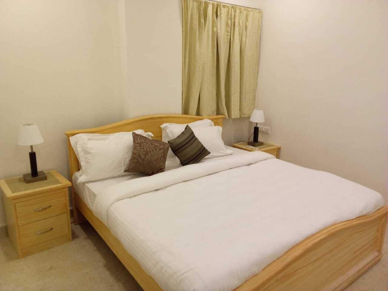 A single bed with a wooden frame, white bedding, and two bedside tables with lamps.