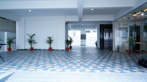 A spacious lobby with a patterned tile floor, potted plants, and a glass wall. - Enkay Service Apartment (Hyderabad)