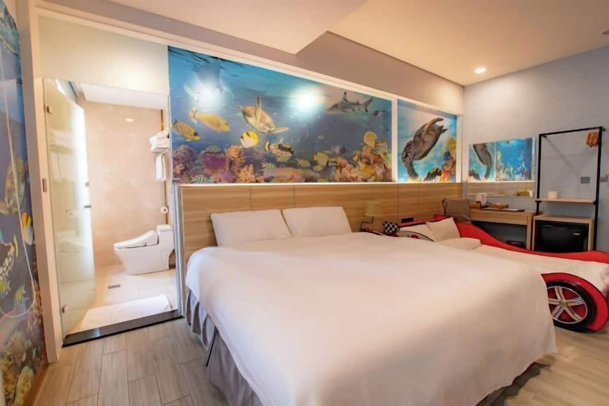 Une chambre d’hôtel avec un lit, une douche et une fresque murale représentant la vie marine.