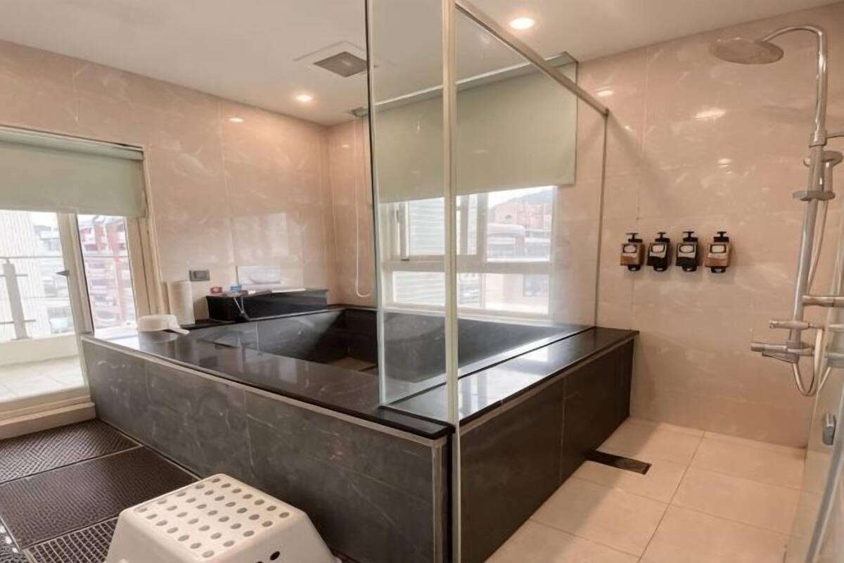 Une salle de bain moderne dotée d’une douche à parois de verre, d’une grande baignoire et d’une fenêtre offrant une vue sur l’extérieur.