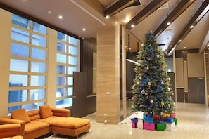 Un moderno vestíbulo con un ventanal grande, un árbol de Navidad y un sofá modular.