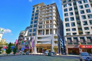 A multi-story hotel with a modern design, featuring balconies on each floor, a central entrance, and a parking area in front. - Muen Yuan Dong Hot Spring Hotel (Yilan)