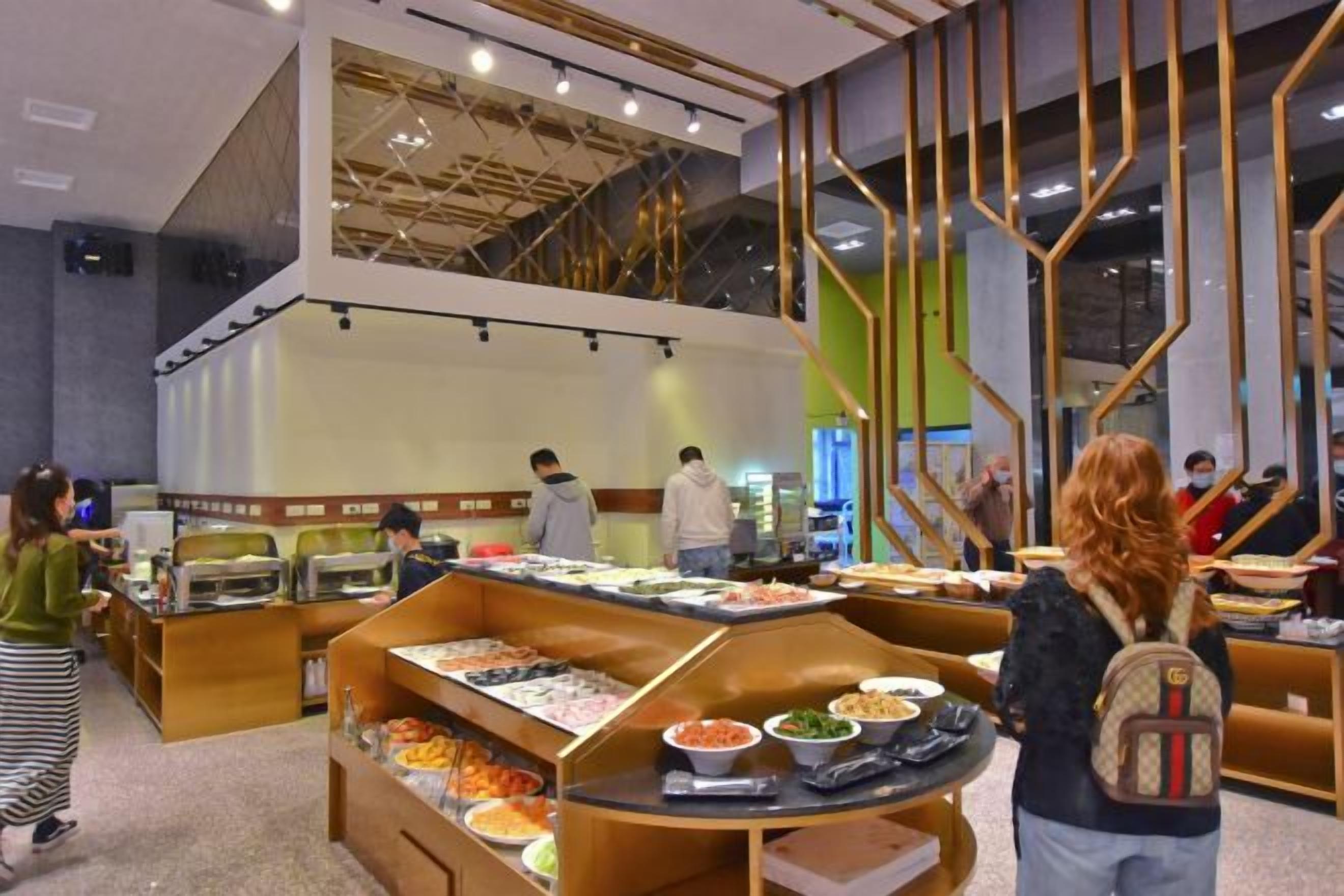 A buffet area with multiple food stations, a staircase, and seating arrangements.