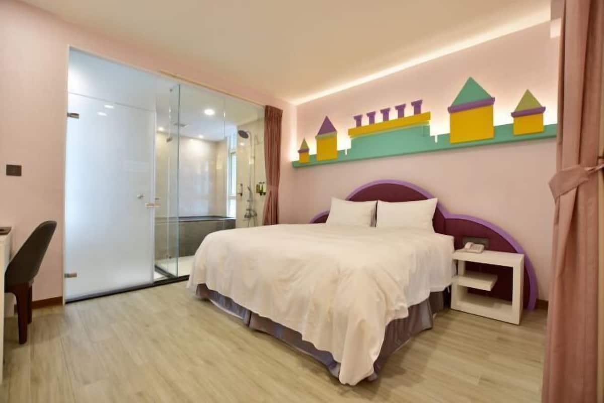 Une chambre à coucher comprenant un lit, une table de chevet, une chaise, une porte en verre et un mur orné de motifs géométriques colorés.
