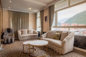 A room with two sofas, a small round table, and a view of a cityscape through large windows.
