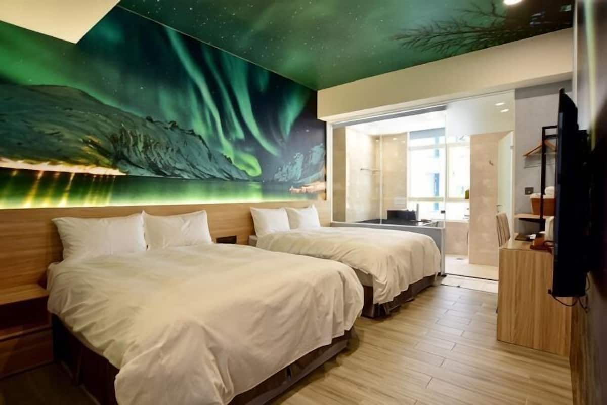 Une chambre d’hôtel avec deux lits, une fresque représentant les aurores boréales et une vue sur la ville.