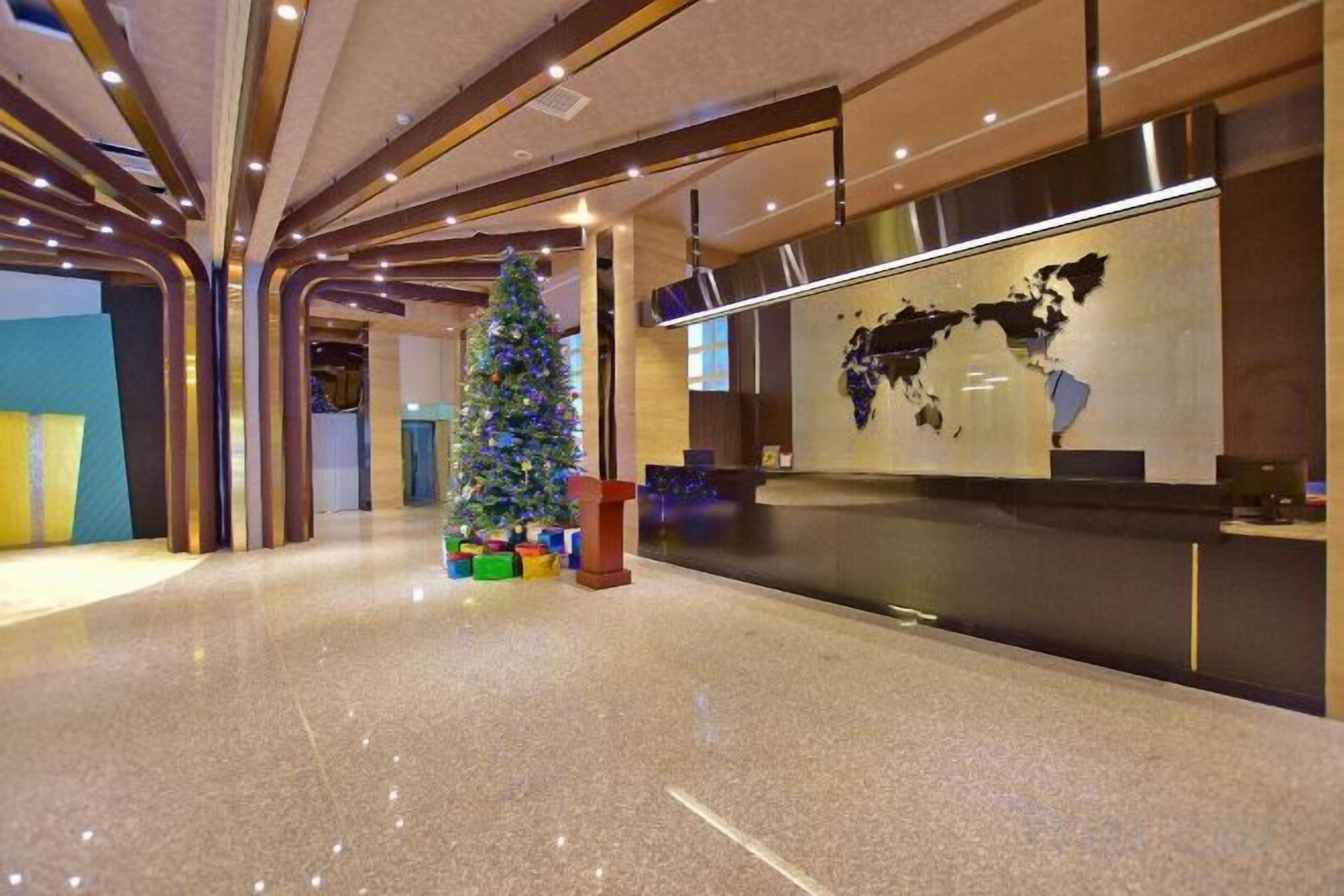 A modern hotel lobby with a polished floor, a reception desk, and a Christmas tree.