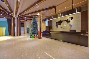 Un moderno vestíbulo de hotel con piso pulido, una recepción y un árbol de Navidad.