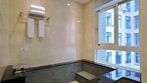 Een moderne badkamer met een groot raam, een handdoekhouder en een zwart badmeubel.
