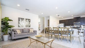 Una sala moderna con sofá, mesa de centro y comedor con sillas y una mesa.