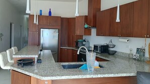 A modern kitchen with granite countertops, wooden cabinets, and stainless steel appliances. - BEACHFRONT NEWLY BUILT 3 BD 2 BA SURFPOINT SWEEPING OCEAN VIEW HOME! SW SWELLS! (Ensenada)