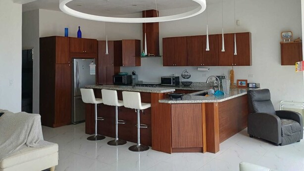 A modern kitchen with a central island, bar stools, and a built-in refrigerator. - BEACHFRONT NEWLY BUILT 3 BD 2 BA SURFPOINT SWEEPING OCEAN VIEW HOME! SW SWELLS! (Ensenada)