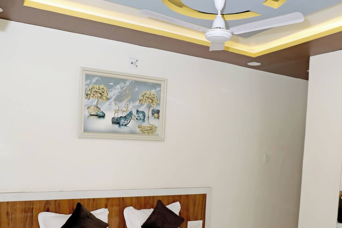 Une chambre à coucher avec un lit, un ventilateur de plafond et un tableau accroché au mur.