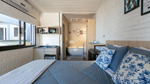 Une petite pièce comprenant un lit, une petite table, un lavabo et une baignoire.