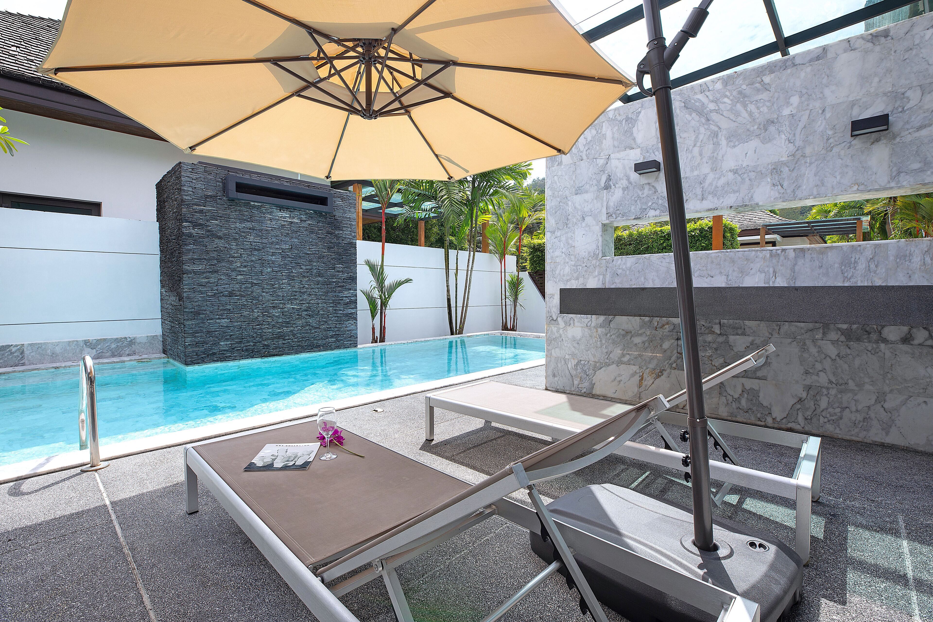 A poolside area with lounge chairs, a table, and an umbrella.