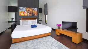 A modern bedroom with a large bed, a flat-screen TV, and artwork on the wall. - Elegant 3BR Pool Villa Coco B6 in Kamala (Kamala)