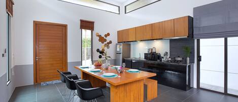 A modern kitchen with wooden cabinets, a central island, and a dining area with chairs.
