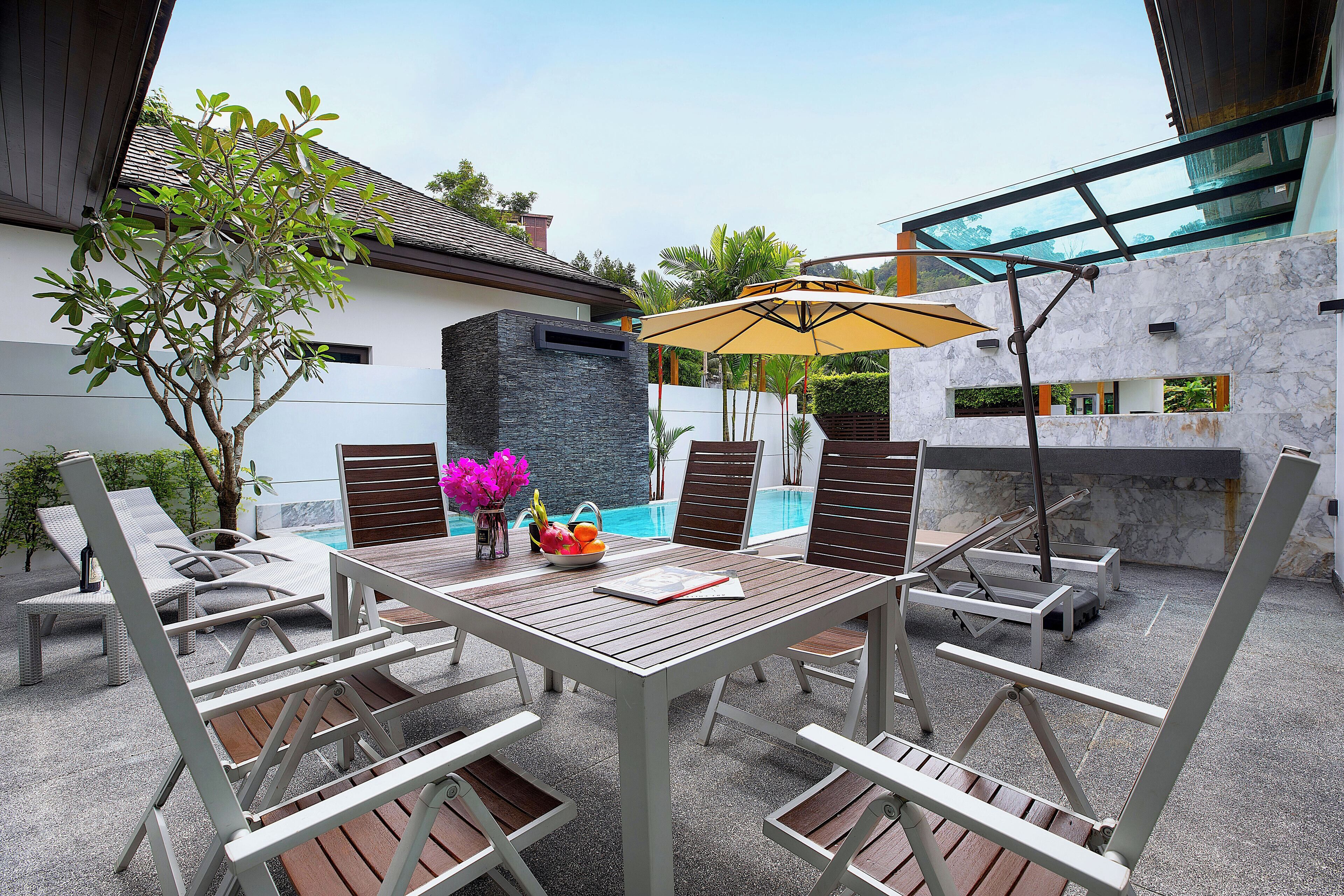 A patio with a table, chairs, and an umbrella.