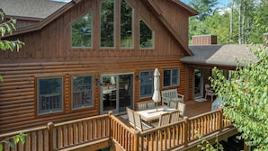 A wooden cabin with a deck, large windows, and outdoor furniture. - Dog Friendly Mountain Retreat w/ Bar & Hot Tub (McHenry)