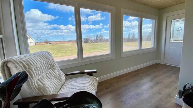 A room with a large window, a wooden ceiling, and a white chair. - Charming Farmhouse on 2 acres, Sleeps 8. Only 5 mins from Richards Point beach (Borden-Carleton)