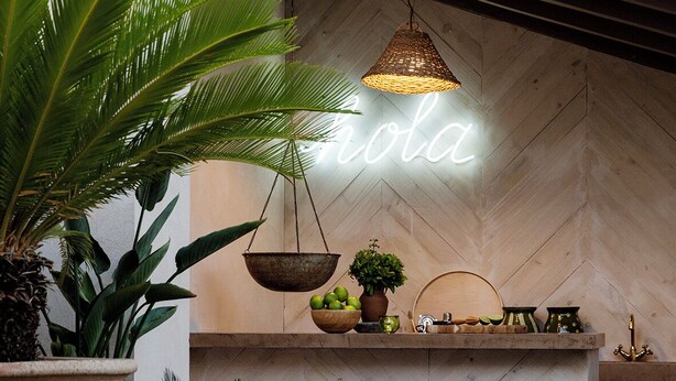 A modern interior with a neon sign, a hanging light fixture, and a herringbone-patterned floor.