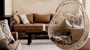 A cozy living room with a hanging chair, a round mirror, and a sofa.